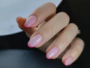 Manicure żelowy z niecodziennym różowo-brązowym frenchem. Paznokcie pokryte naturalnym, przezroczystym żelem. Na końcach płytek paznokci widać podwójny pasek łączący delikatny róż z brązem, tworzący efektowny double french. Taki akcent nadaje stylizacji wyjątkowego i modnego charakteru. Pozwala osiągnąć zarówno elegancki jak i niebanalny wygląd paznokci.